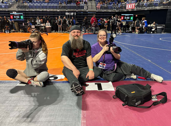 Riley Rayome (left) takes photos during a tournament earlier this season as her father and The Woodlands wrestling coach Jeff Rayome and her mother Amanda sit on the mats. Photo by Carissa Mooney of Phlox Photography